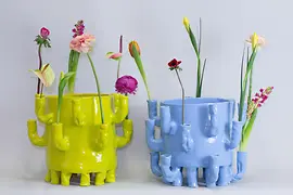 Zwei farbenfrohe Keramikvasen von Onka Allmayer-Beck mit Frühlingsblumen.
