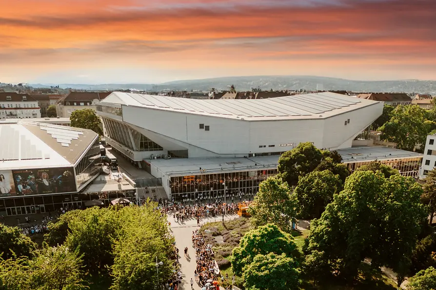 Luftaufnahme der Wiener Stadthalle in Abendstimmung, Menschen warten auf den Einlass