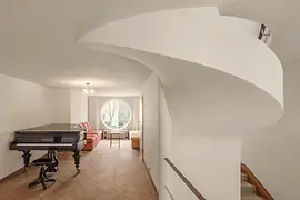 Salle de musique avec piano à queue, fenêtre ronde et sièges.