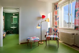 Coin salon dans la chambre d'amis avec fauteuil à motifs et lampadaire.