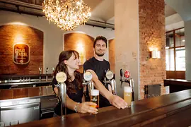 Dos personas con cerveza detrás de la barra.