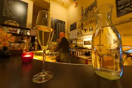 Szigeti Sektcomptoir, Innenansicht mit einem Glas Sekt und Gästen 