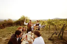 Heuriger Wieninger en Nussberg: gente comiendo y bebiendo al aire libre y dos músicos de Wienerlied.