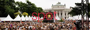 Spot is written in large red letters in the middle of the picture, the name of the event brochure, the picture shows an event in front of the Burgtheater