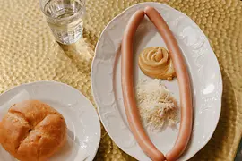 Deux assiettes, l'une contenant deux saucisses de Vienne, l'autre un petit pain rond
