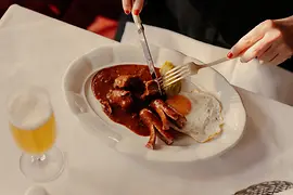 Une assiette de goulasch avec pommes de terre au sel, œuf au plat et mini-saucisse
