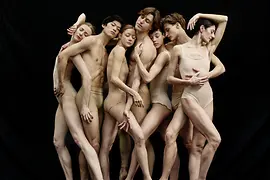 Sieben Ballettänzerinnen und -tänzer eng beieinander stehend in Pose.