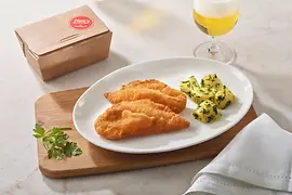 Escalope a la vienesa de pollo con patatas con perejil sobre una tabla de madera y una cerveza.