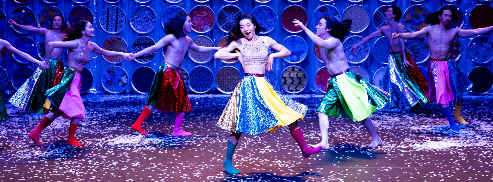 Ballerini e ballerine coreani volteggiano sul palco con gonne colorate e stivali.
