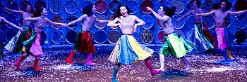 Des danseurs et danseuses coréens virevoltent sur scène, vêtus de jupes colorées et de bottes.