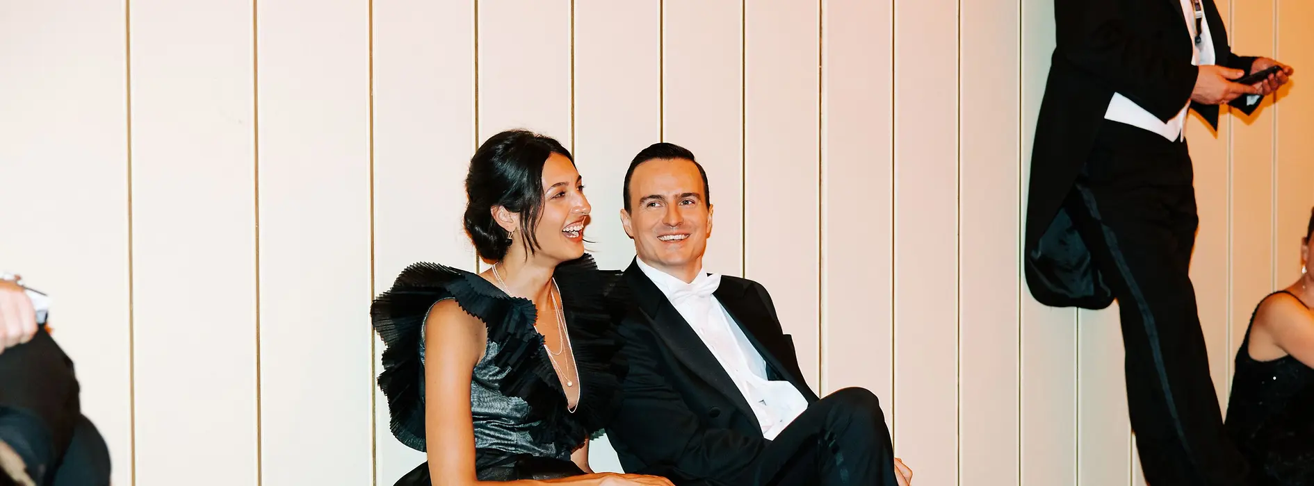 Couple in ball attire sitting on the floor and recovering from dancing