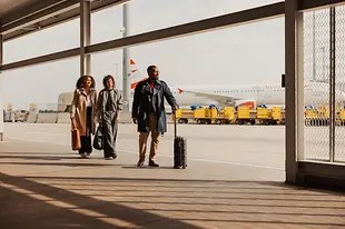 携带手提行李的人们在维也纳机场的户外区域前往航站楼