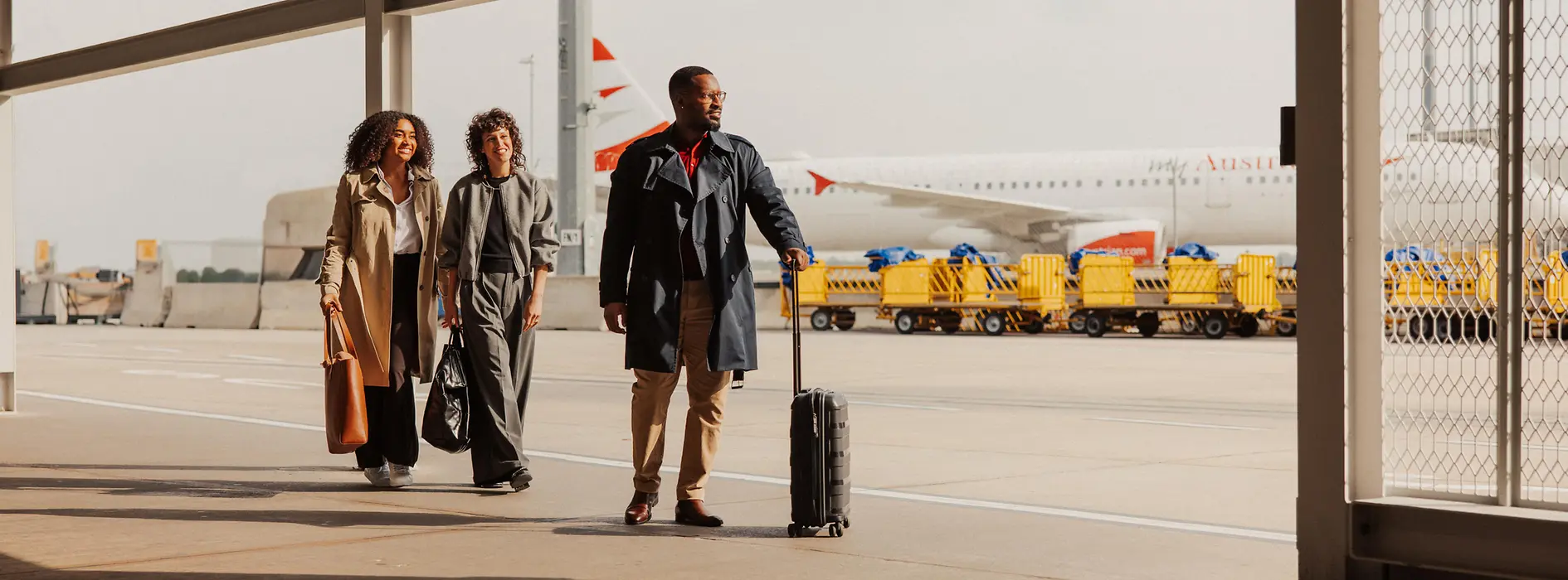 Personnes avec des bagages à main dans la zone extérieure de l'aéroport de Vienne en route vers le terminal.