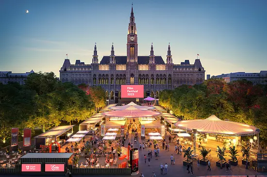 Evening aerial view of the 2025 Film Festival in front of Vienna City Hall with numerous stalls.