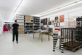 A view into the archive with shelves, a table, and a cage