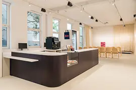 The forum of the queer center Qwien with a counter, a coffee machine, and chairs